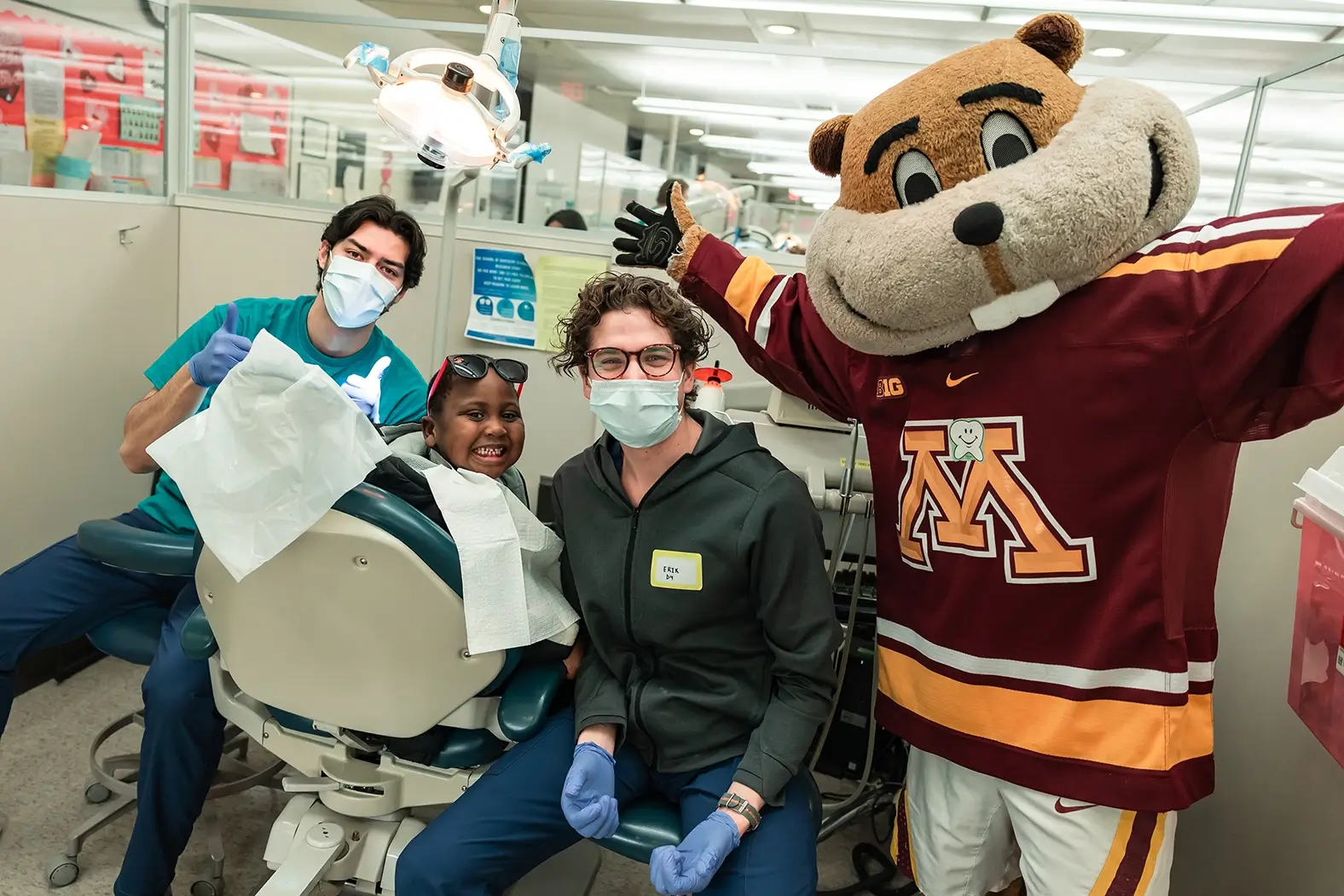Two dental students, a child patient, and Goldy Gopher at Give Kids a Smile Give Kids a Smile with Goldy Gopher